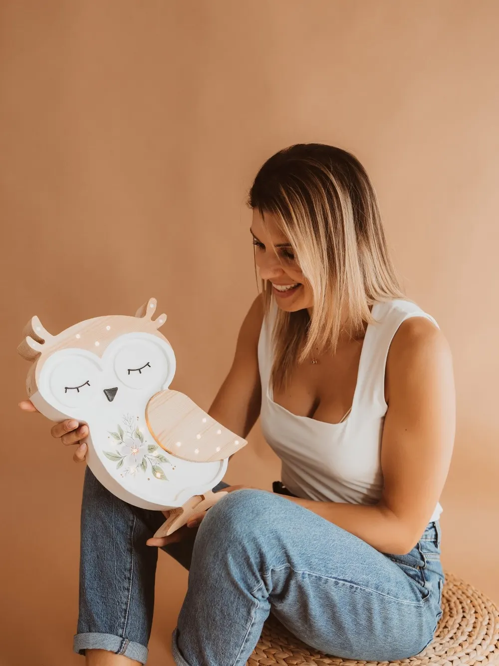 Cathia in the workshop, holding a wooden owl